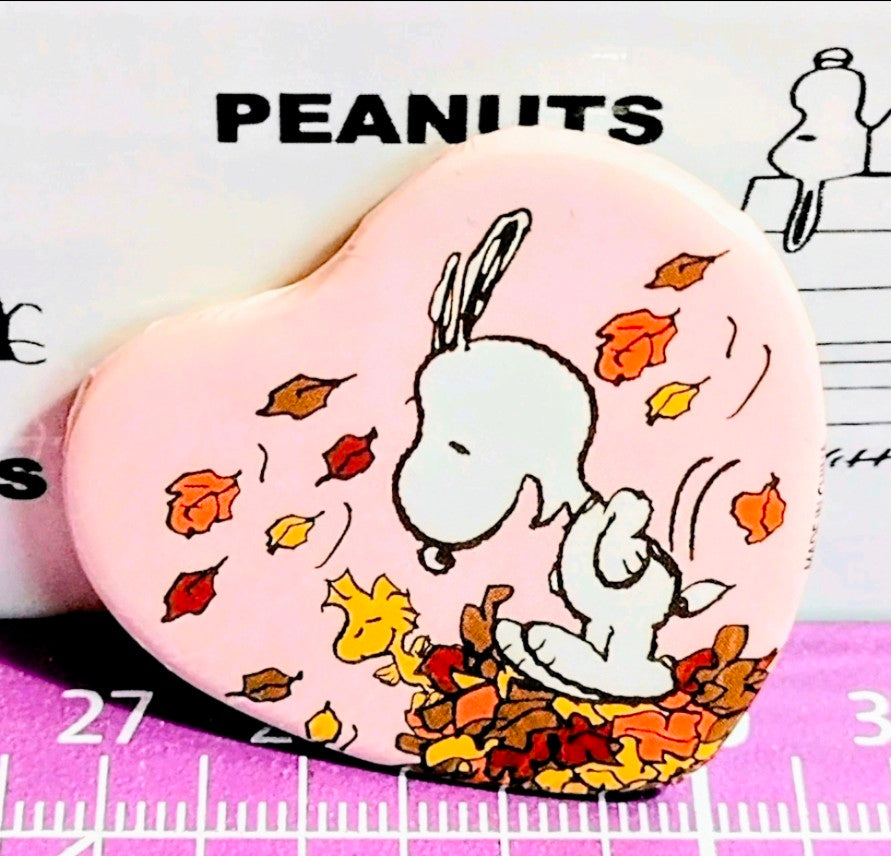 Round Snoopy phone grip with autumn leaves illustration on a PEANUTS card.