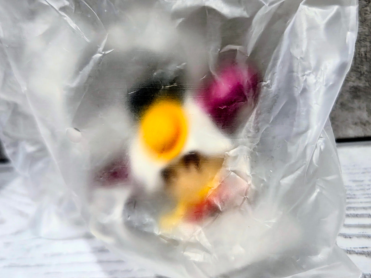 Close-up of mini figure parts in a white plastic bag, with pink and black accents.