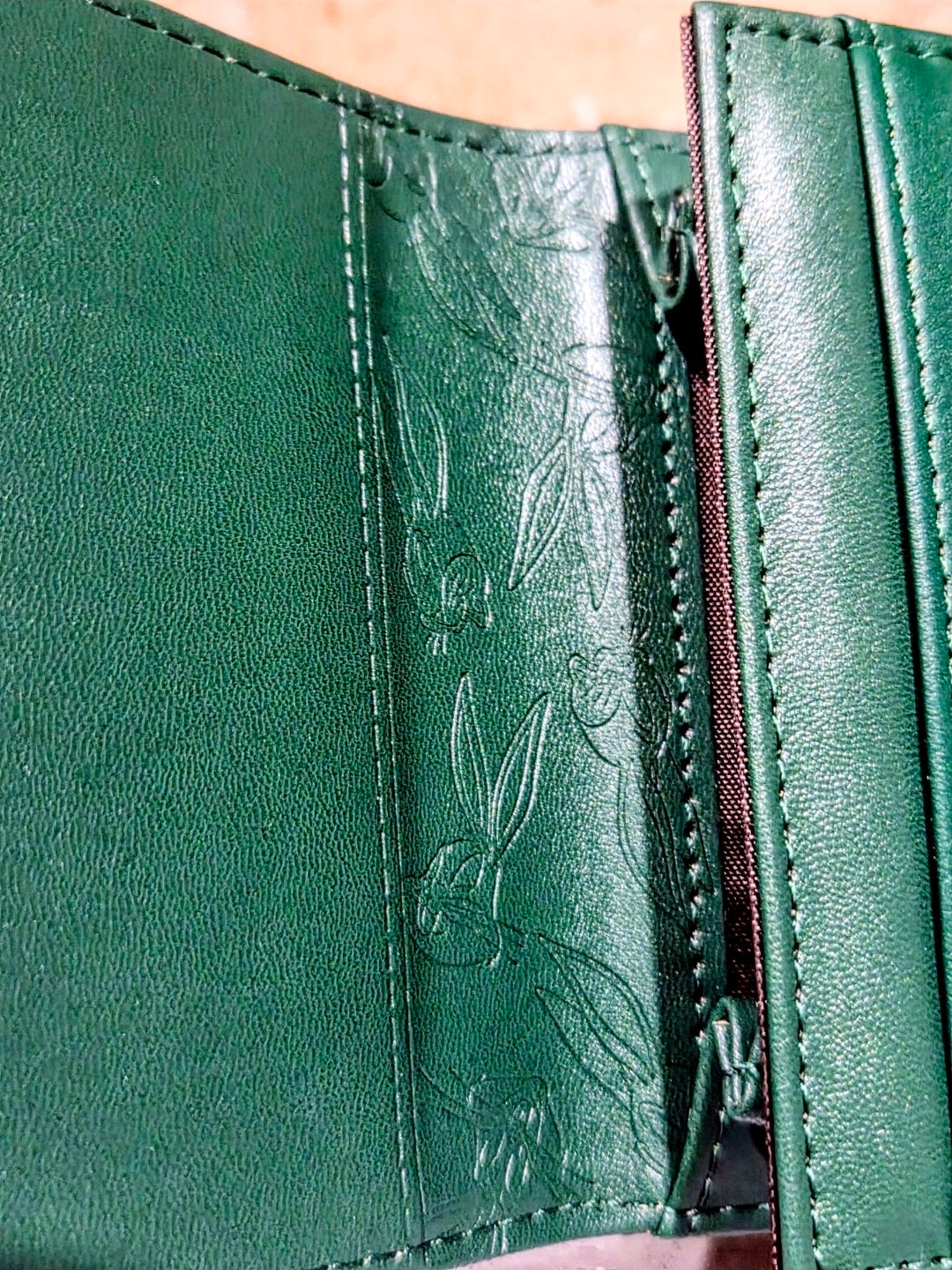 Green faux leather wallet close-up of stitched panel and engraved Bugs Bunny
