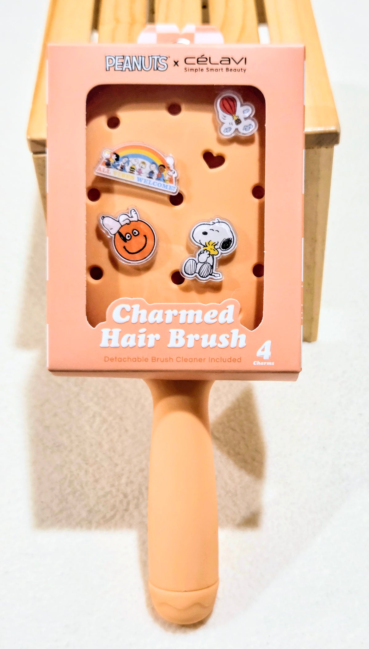 Peach paddle hair brush with Peanuts x Celavi charm characters on the front box