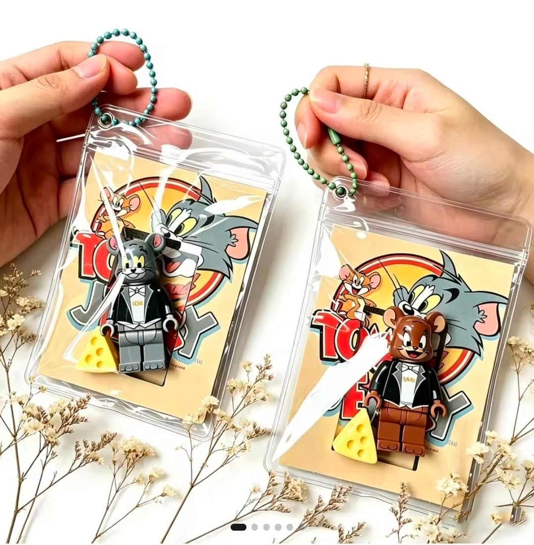 Pair of clear keychain pouches with bead rings, showing gray Tom and brown Jerry