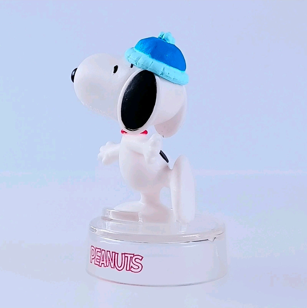Snoopy figure wearing blue cap, white bodysuit, clear PEANUTS base