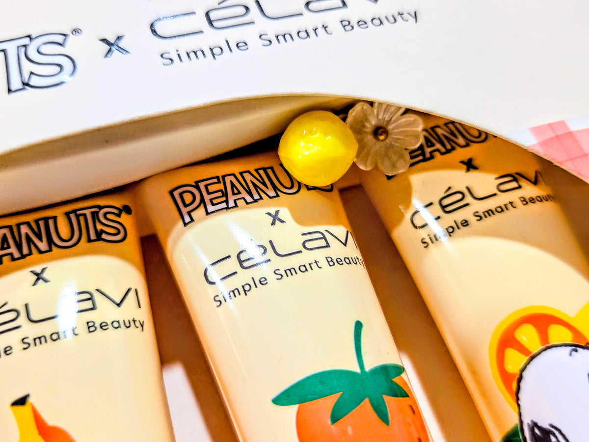 Fruit lip gloss tubes in gift box: yellow cap and orange-brown tubes, close-up