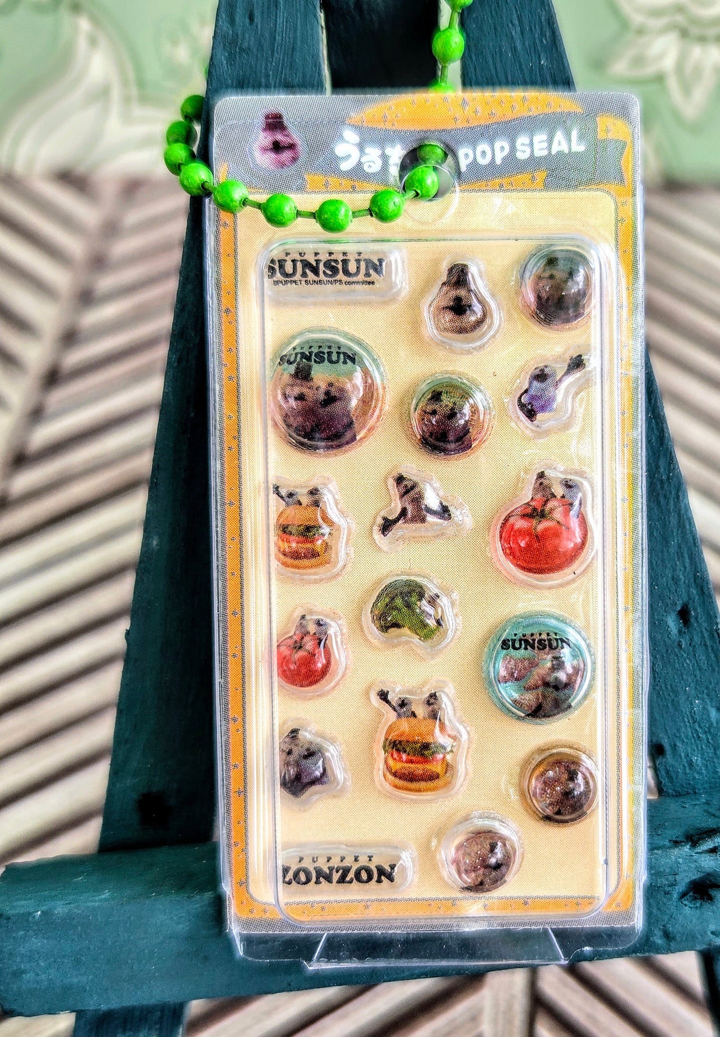 Clear blister sticker keychain pack hanging from green and pink bead strings