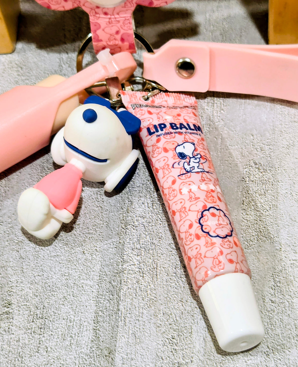 Snoopy keychain figure with lip balm tube attached to pink strap