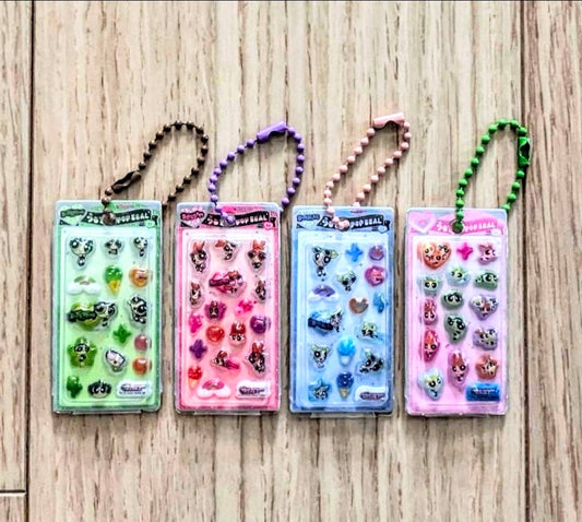 Set of four character 3D resin keychain blister packs with bead necklaces on wood