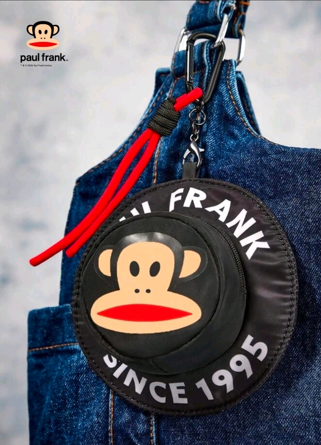 Round black monkey-face coin pouch with zipper, red cord tassel, and hanging clip