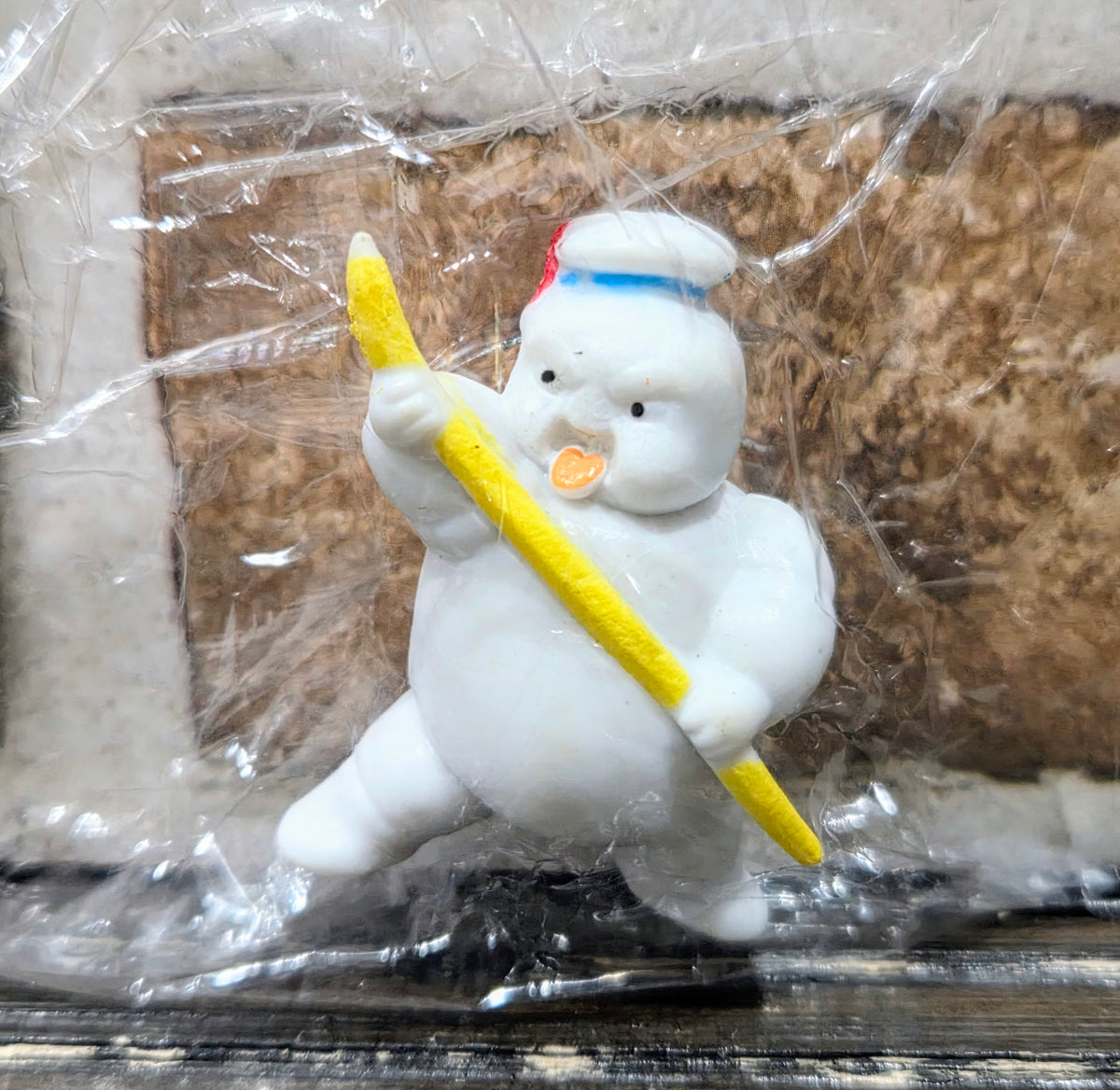 White mini figure close-up, blue bib and yellow wand, clear plastic bag