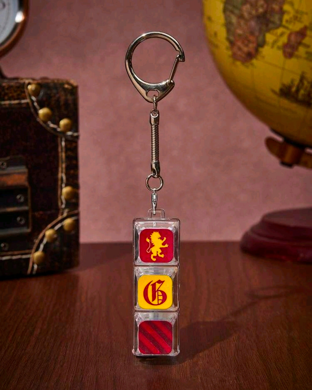 Clear stacked keycap charm on a metal spring, lion top, crest middle, red striped bottom