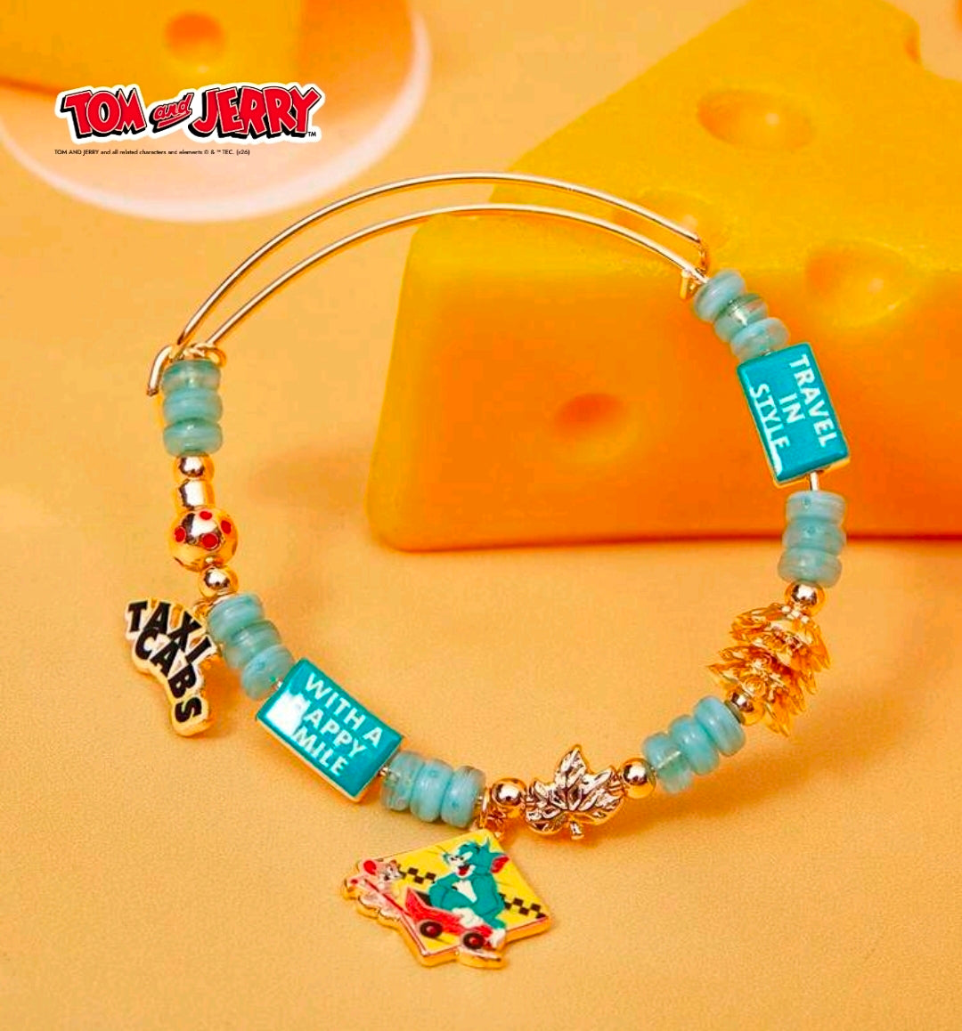 Gold-tone teal bead bangle bracelet with travel bottle, happy smile tag, and taxi cab charm
