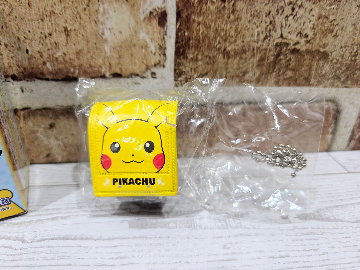 Yellow Pikachu face charm in a clear bag with metal chain accessory