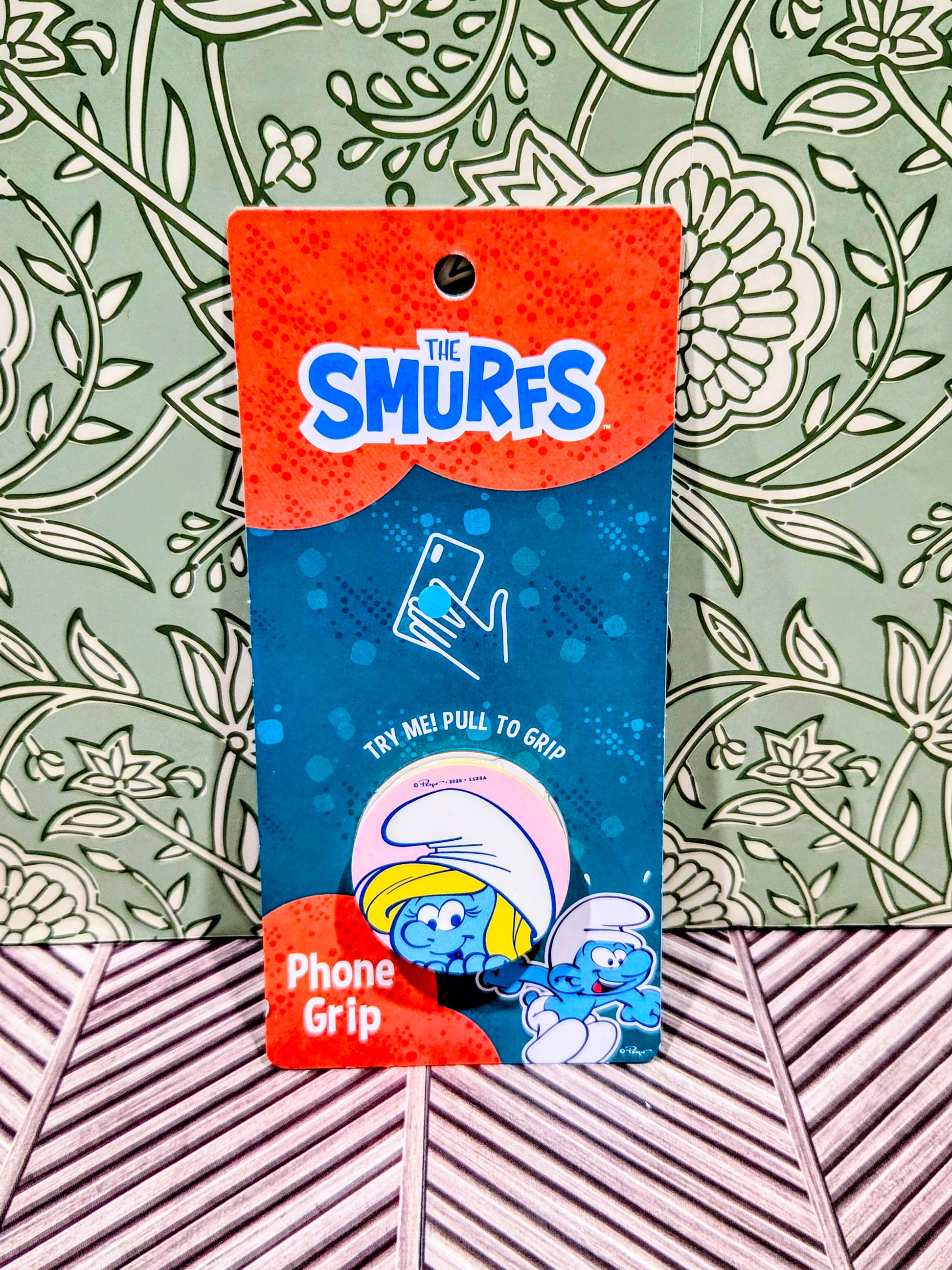 Smurf phone grip holder on blue packaging with The Smurfs logo and try me graphic