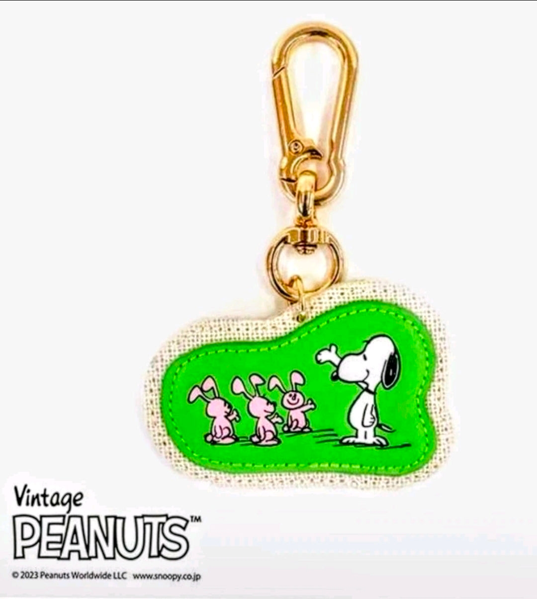 Green Snoopy keychain with bunnies on beige fabric, gold clasp ring