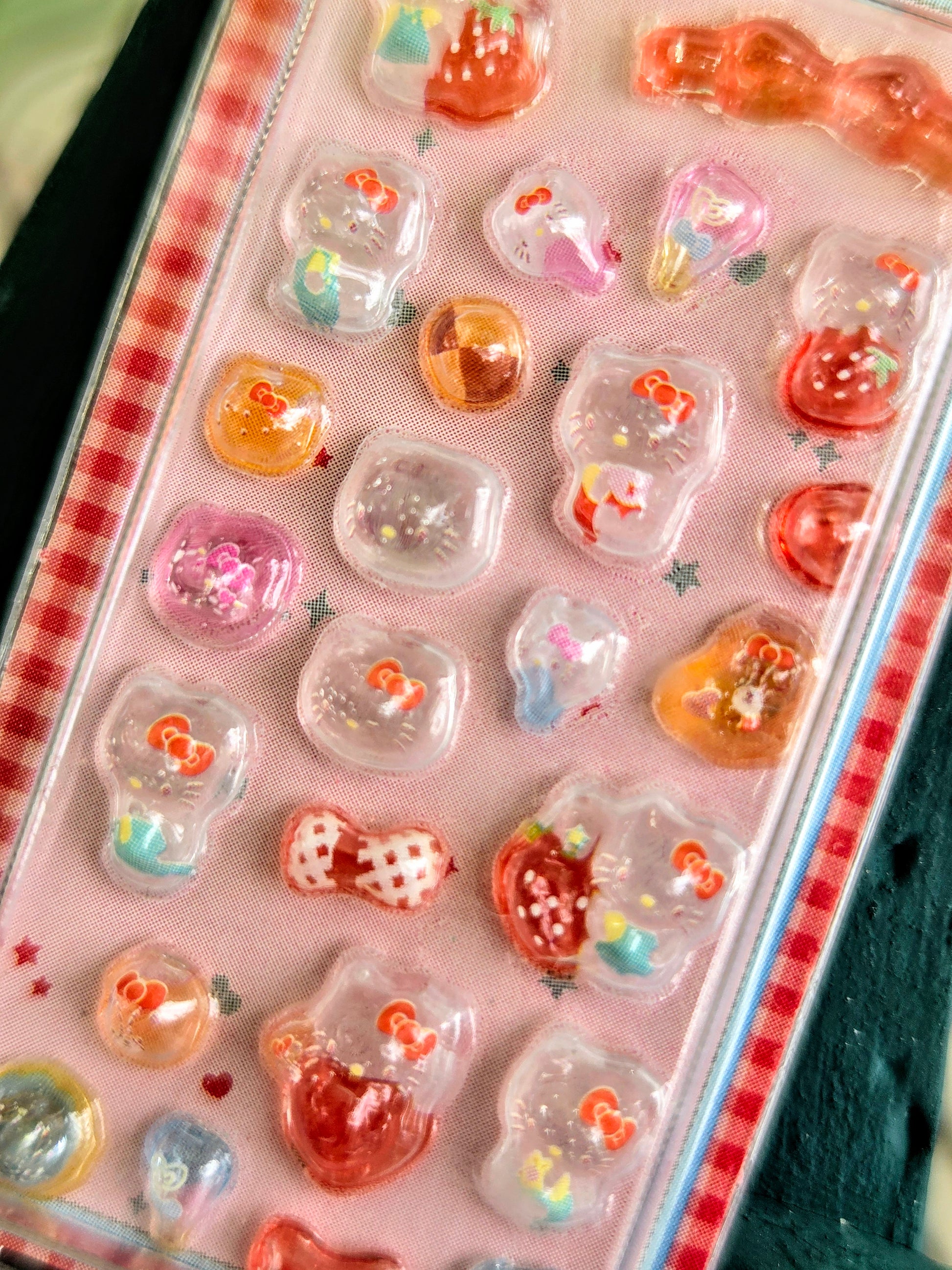 Close-up of red-orange 3D character and heart stickers inside a clear blister pack