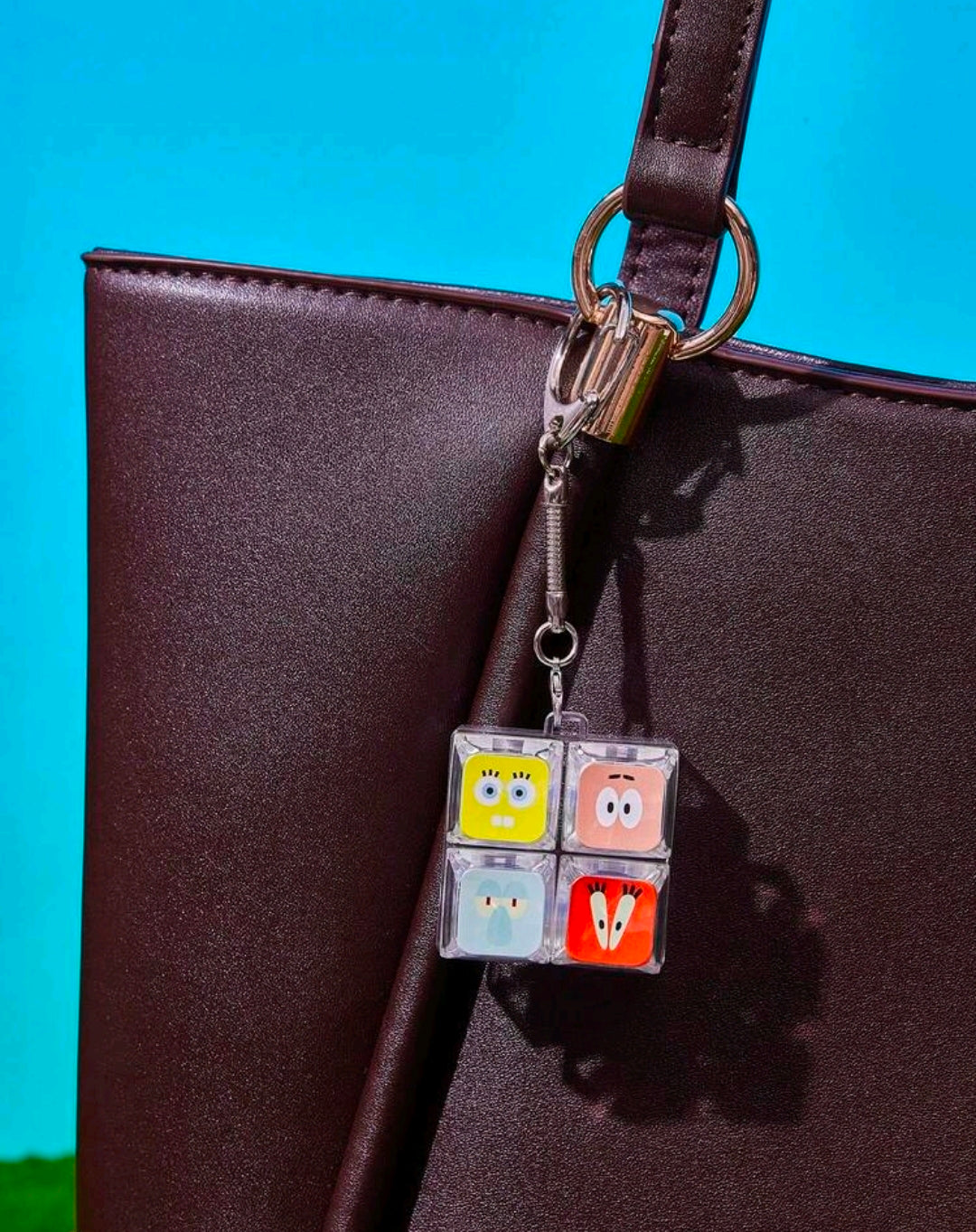 Clear 2x2 SpongeBob fidget keychain charm hanging from a brown strap with metal hook