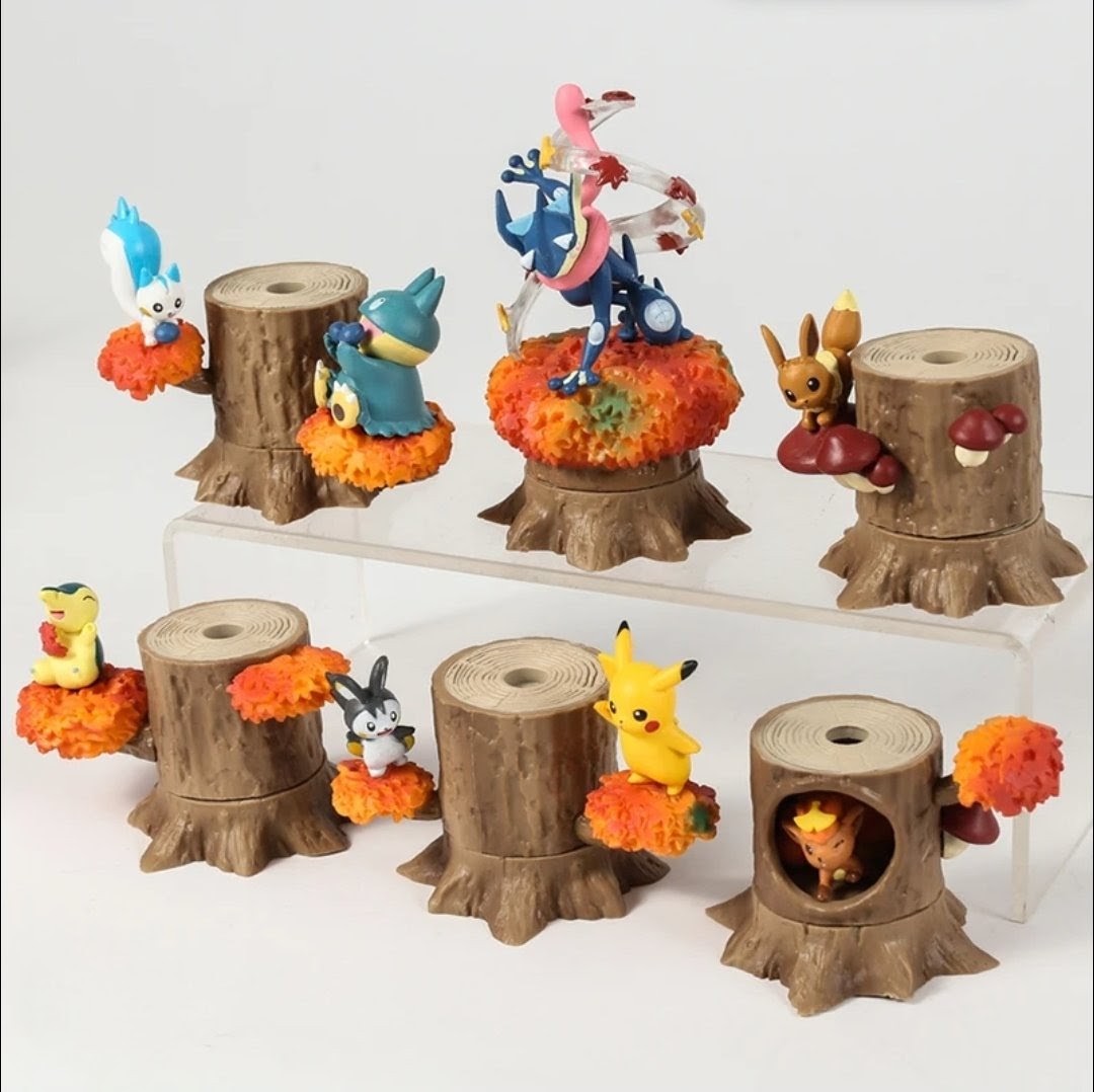 Assorted tree-stump figures with autumn leaf bases arranged on a white display tray