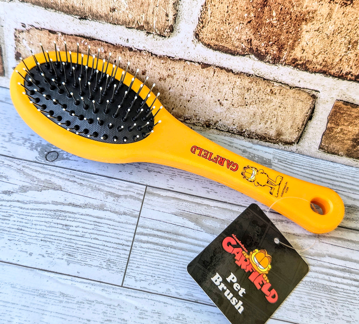 Yellow pet brush with black bristle pad and Garfield “Pet” brush tag