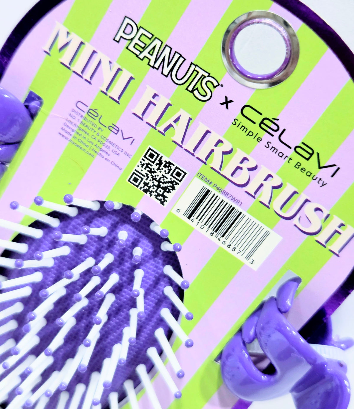 Mini hairbrush with purple bristles on Peanuts x Celavi striped card packaging