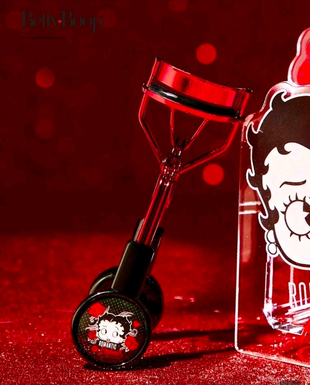 Betty Boop eyelash curler close-up with red metal frame and black handle graphic