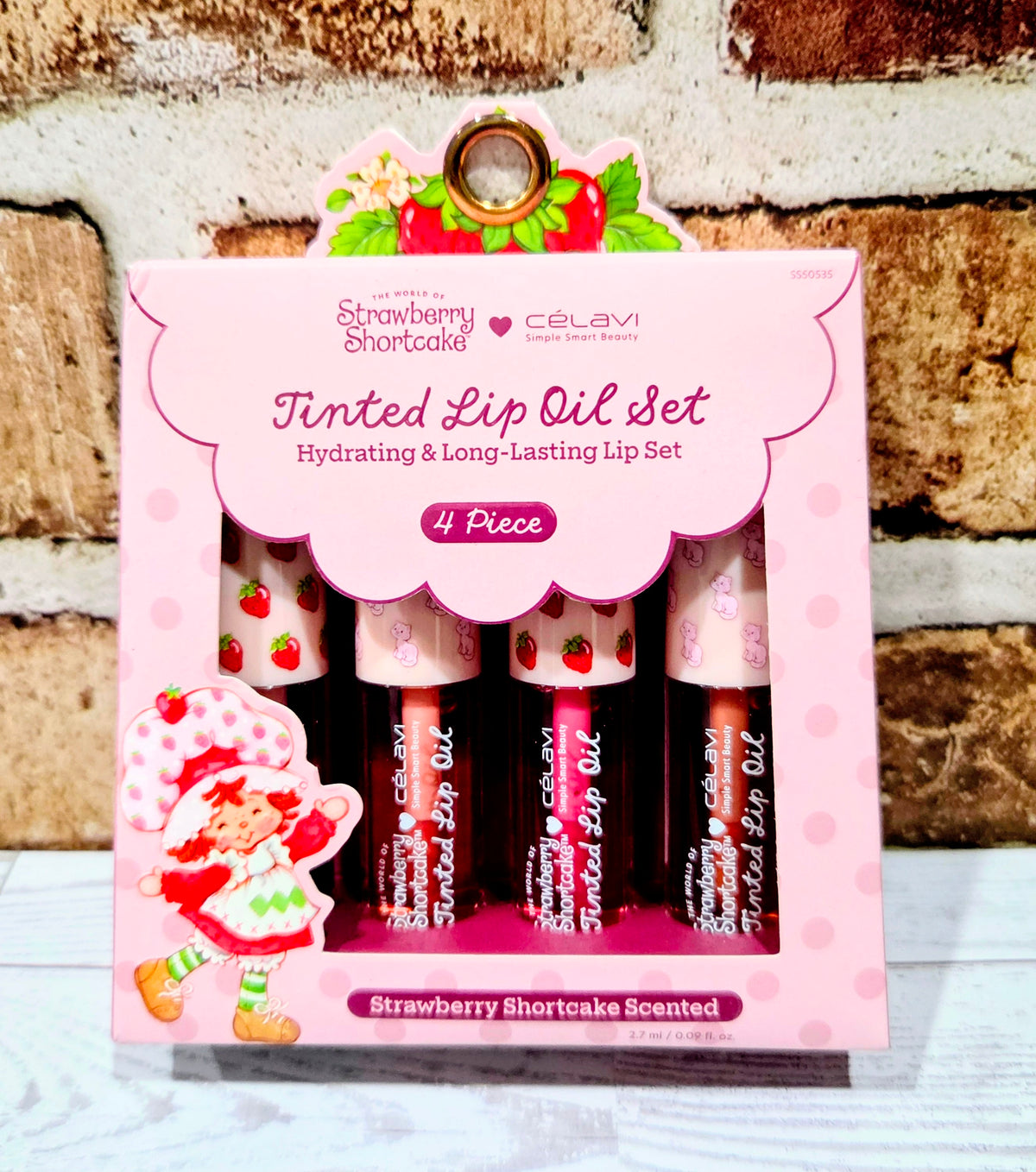 Tinted lip oil set packaging with four lip oil bottles, Strawberry Shortcake scented theme.