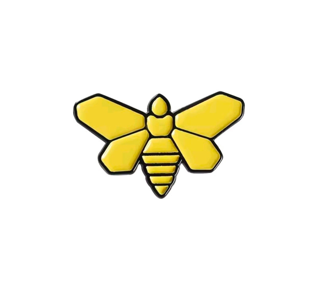 Enamel pin close-up of yellow bee with black stripes and raised center body