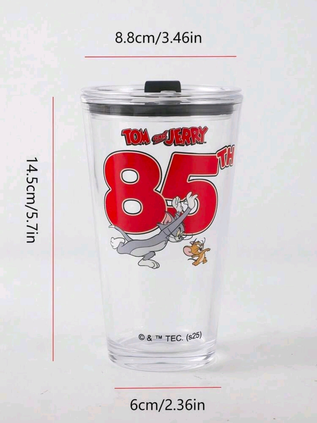 Clear glass tumbler with black lid and Tom & Jerry 85 graphic