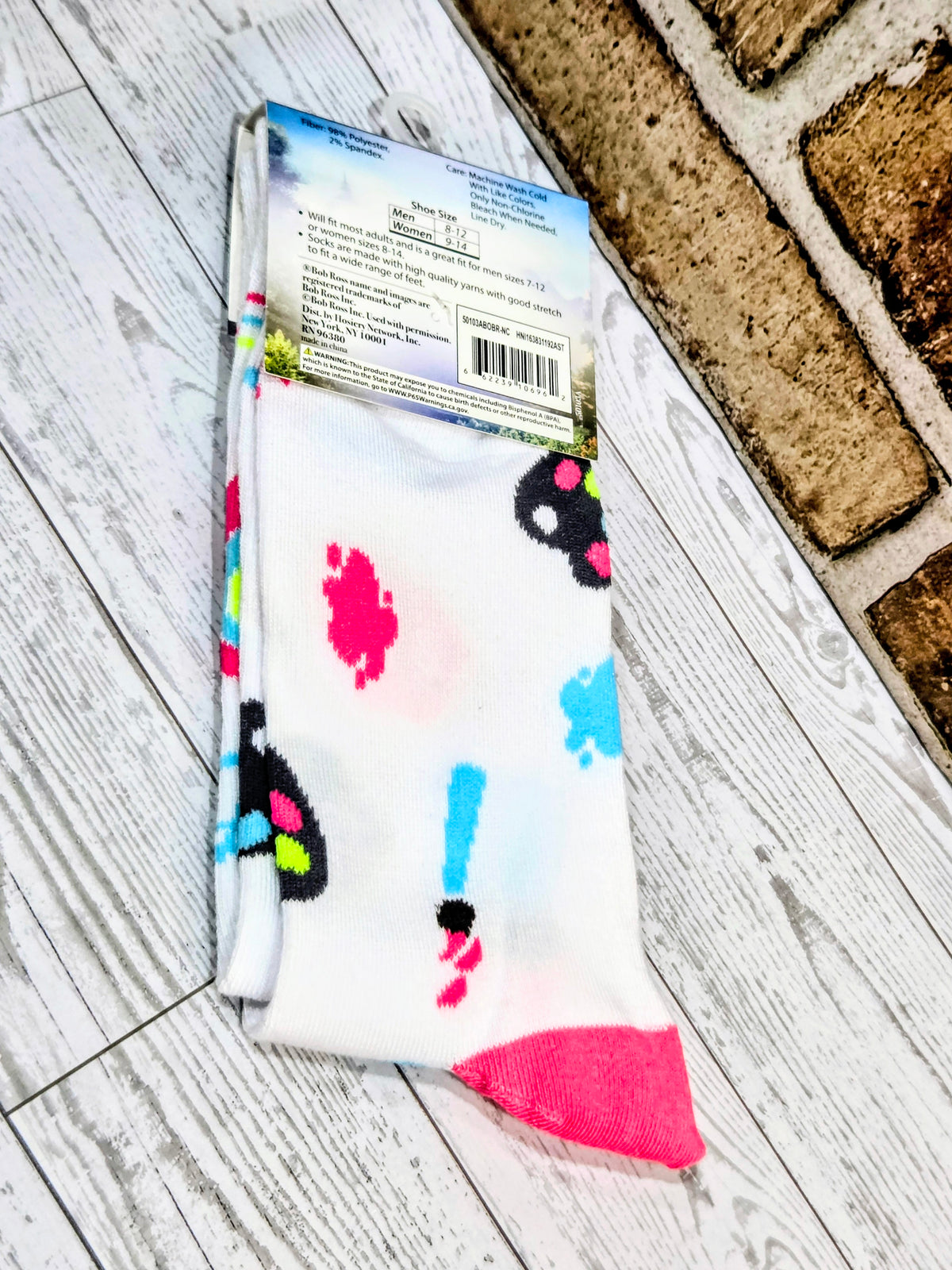 White crew sock with dark and bright paw-print designs and pink heel