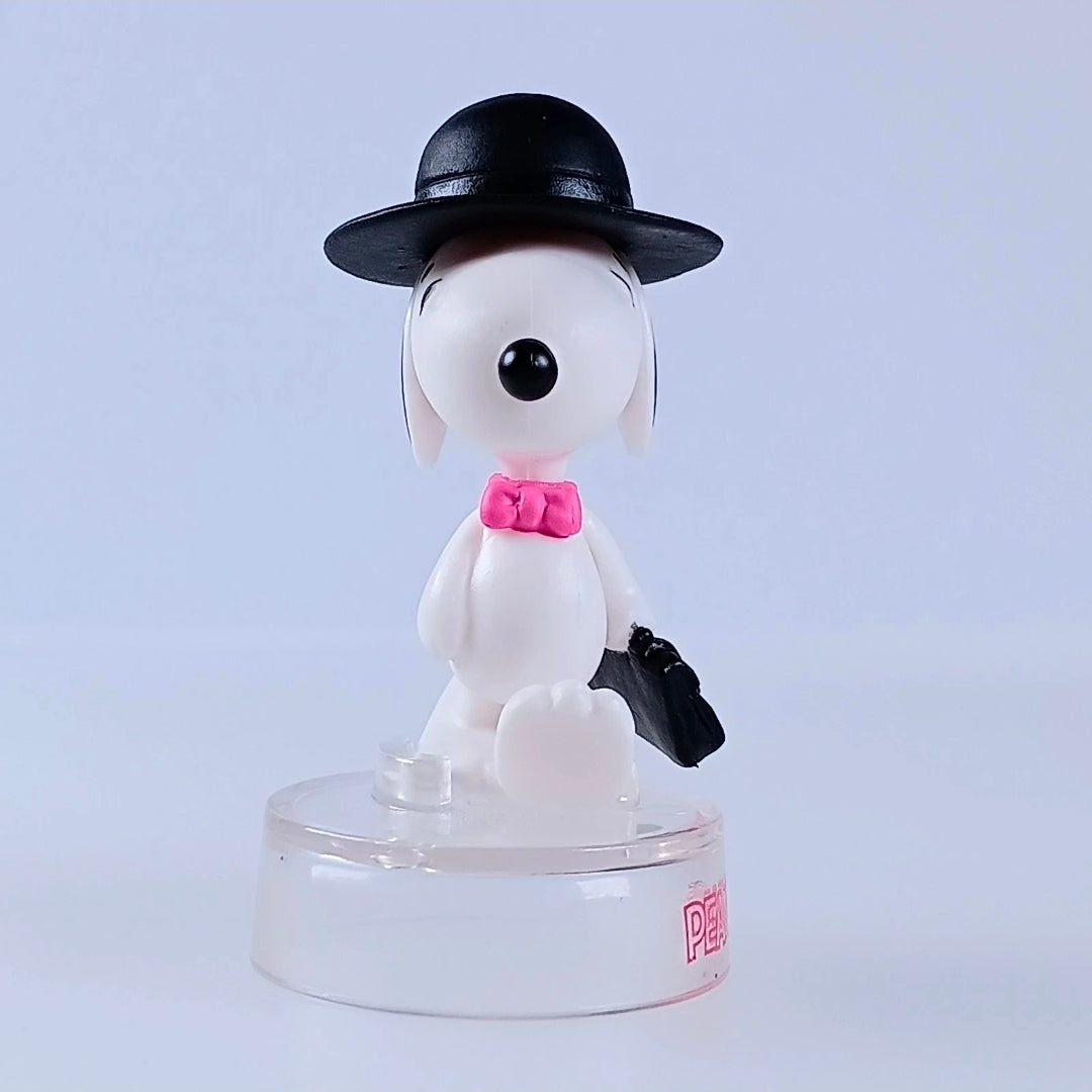 Snoopy figure in black hat and pink bow tie with black bag, clear PEANUTS base