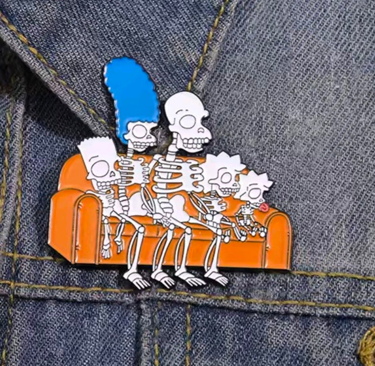 Skeleton couch enamel pin on blue denim fabric