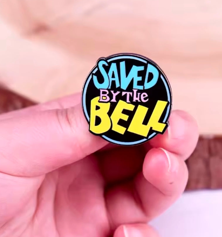 Round enamel pin with multicolor “Saved by the Bell” logo on black
