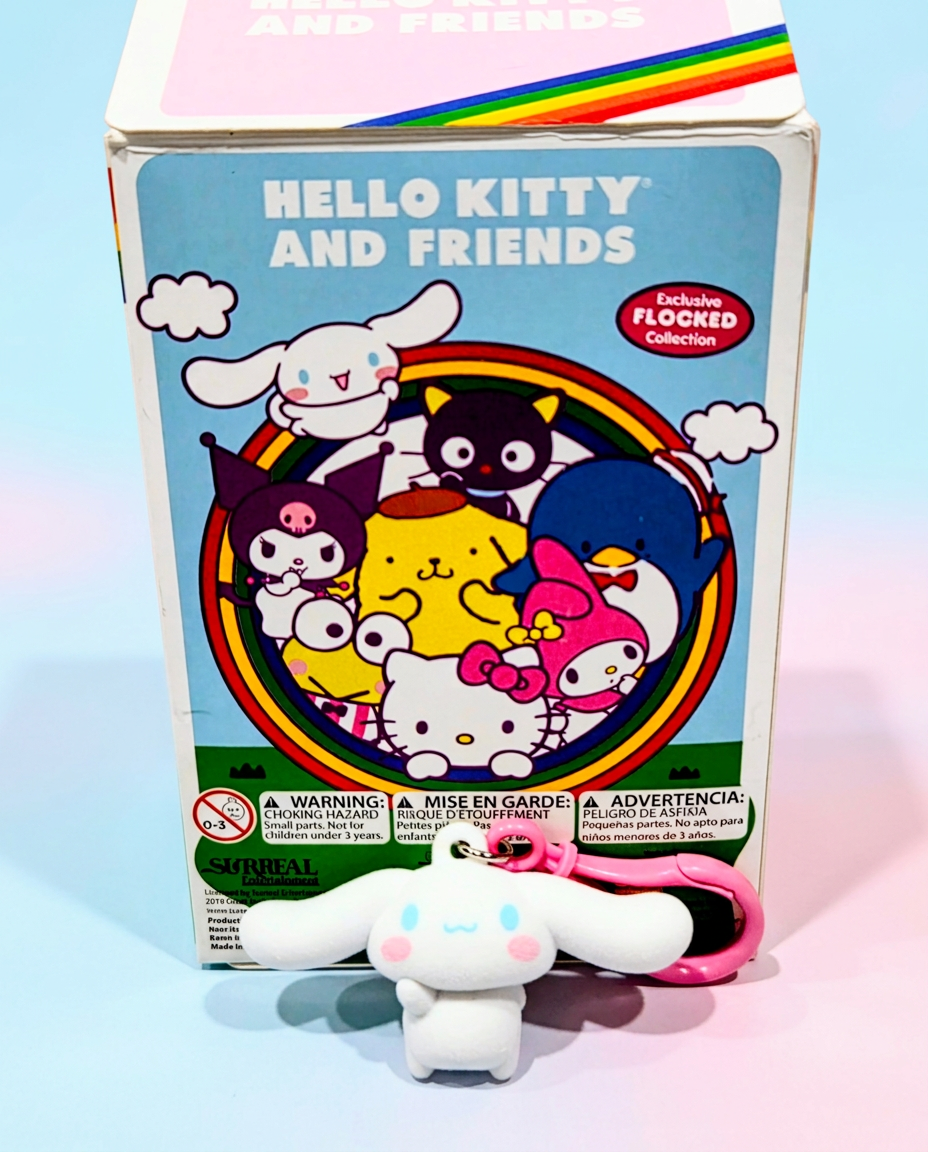 White flocked Hello Kitty character keychain with pink ring, shown in front of box.
