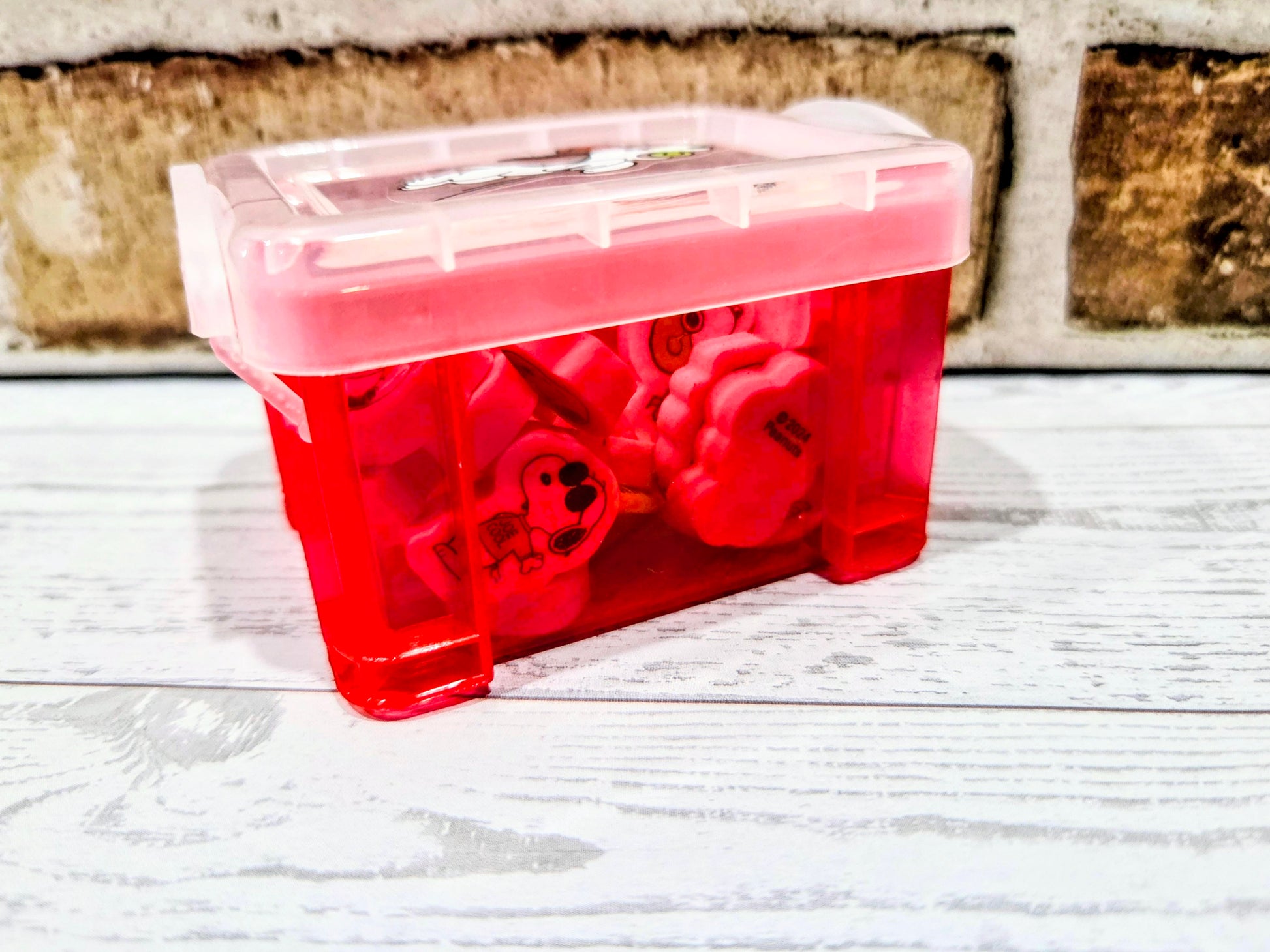 Red desktop organizer box with clear top, Snoopy erasers visible inside