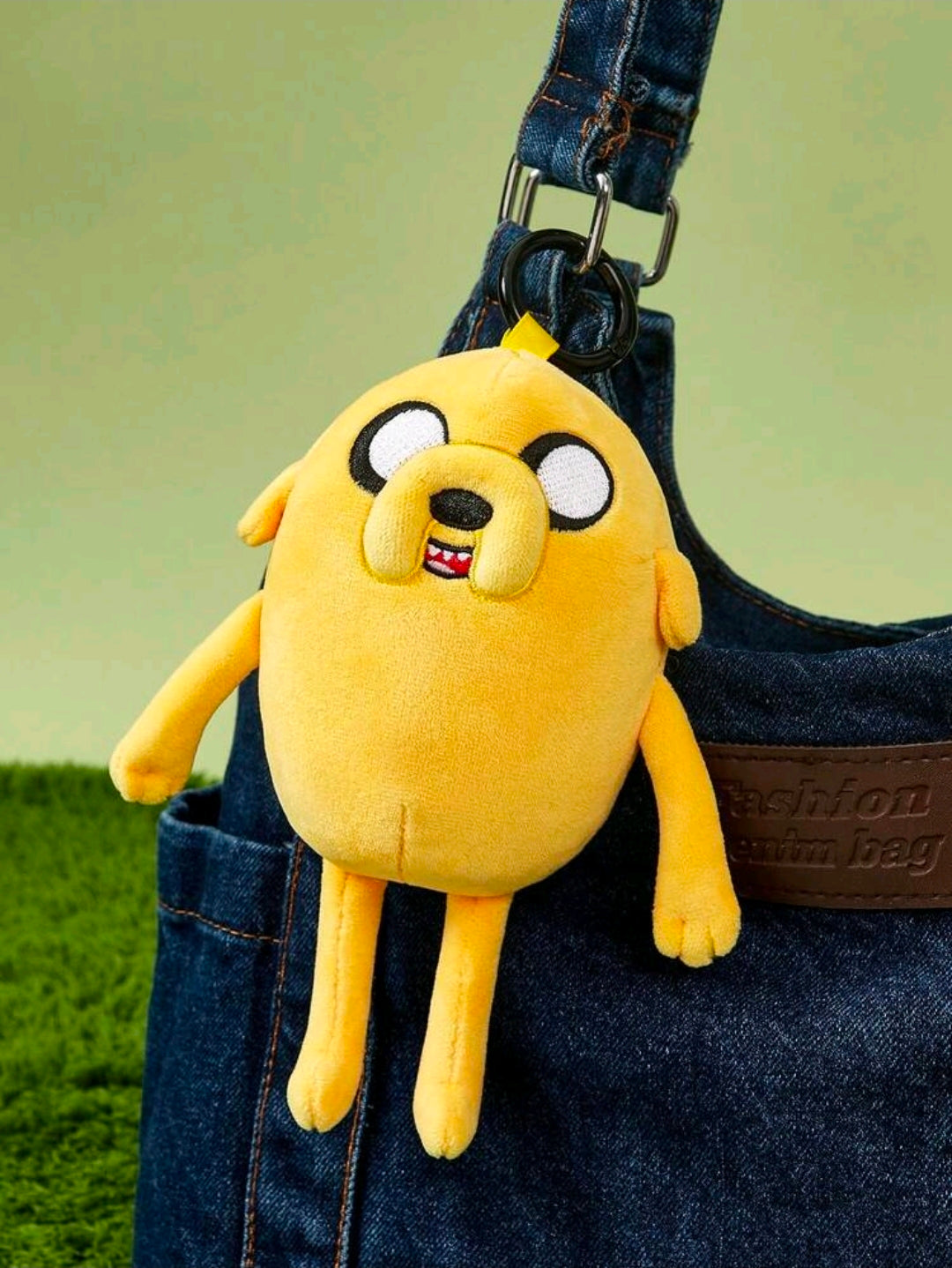 Yellow Jake the Dog plush bag charm keychain clipped on blue denim bag strap.